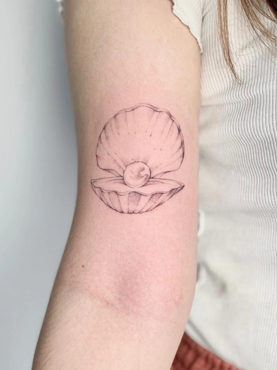 pearl in a shell fine line tattoo on arm