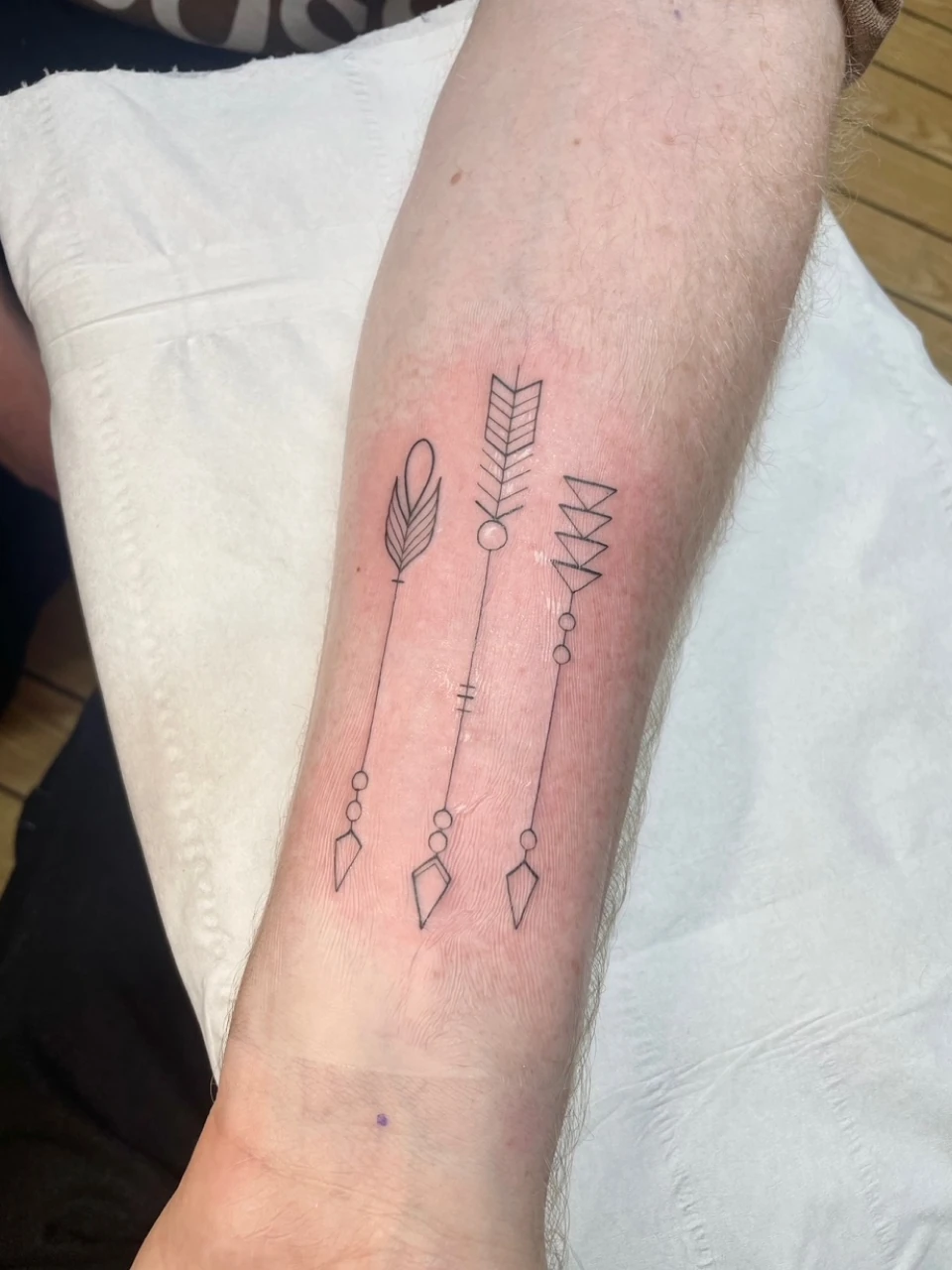 ornamental arrows fine line tattoo on forearm